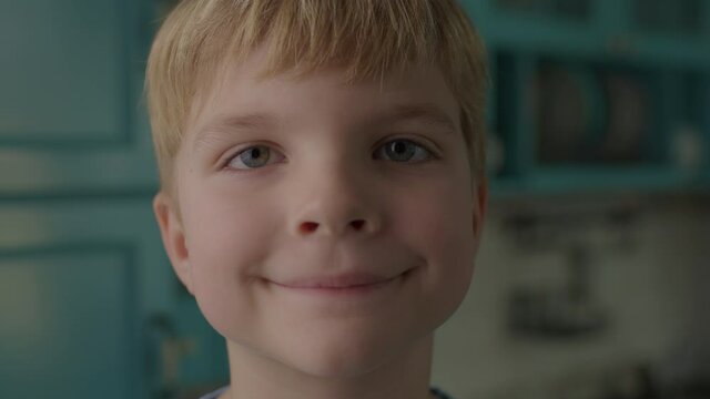 Portrait of smiling preschool boy looking at camera. 6 years old blonde hair kid smiling to camera.