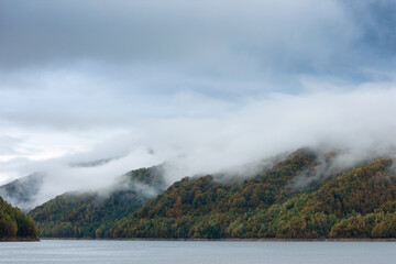 Autumn landscape, fog covering a forest by a lake