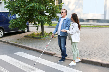 Blind senior man with his daughter crossing road in city - obrazy, fototapety, plakaty