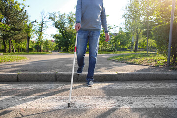 Blind senior man crossing road in city