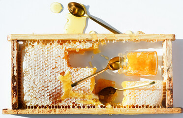 Broken bee honeycomb made of wax with honey inside in a wooden frame on a light background with...