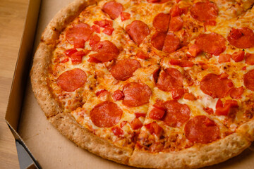 Fresh pepperoni pizza in a box with salami slices delivered home. Fast food delivery from restaurant.