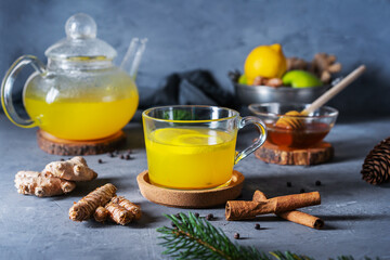 Immune beverage in glass cup, tea pot with ginger, turmeric, cinnamon, lemon, honey and black pepper. Decorated with pins