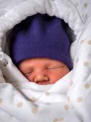 a small child is lying in a blanket in a hat and sleeping