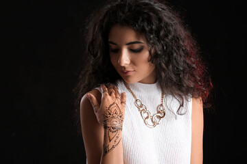 Beautiful Indian woman with henna tattoo on dark background