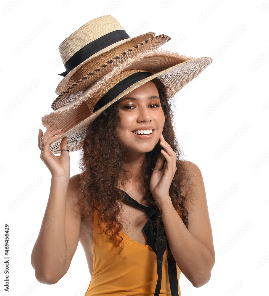 Wall mural beautiful african-american woman in many stylish hats on white background