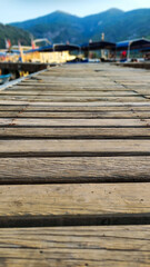 Wooden pier with boats and mountains in the background.