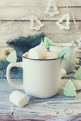 Cups of coffee with meringues and marshmallows, spruce branches, illumination on a wooden background, the concept of celebrating Christmas, New Year, home comfort, congratulations 