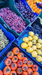 Street market. Fruits and berries in blue trays. Quince, grapes, persimmon. 
