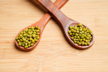 Green gram or mung bean in wooden spoon over wooden background.