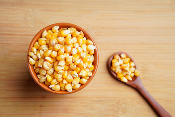 dried corn seeds in wooden bowl and wooden spoon on white background.