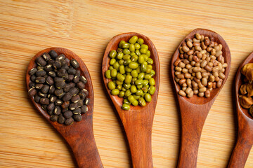 various dried types of bean and pea in wooden spoon.