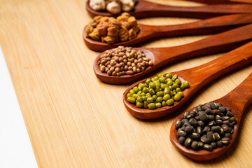 various dried types of bean and pea in wooden spoon.
