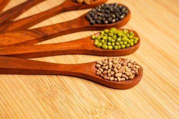 various dried types of bean and pea in wooden spoon.