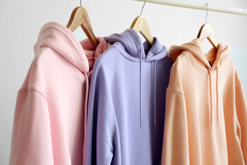 Modern hoodies hanging on light wall