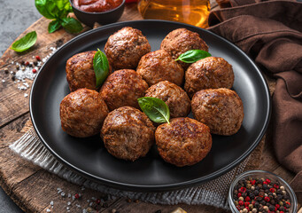 Fried meatballs with fresh herbs close-up on a wooden board.