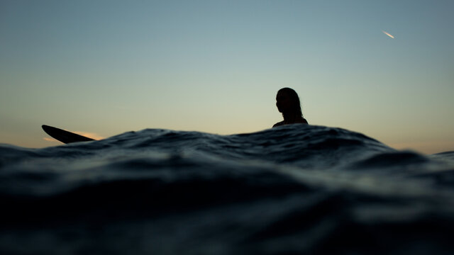 beautiful girl with a surfboard at sunset.