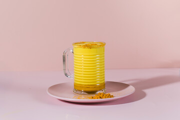 Latte turmeric on a pink background with hard shadows. Moon milk for better sleep. Copy space.