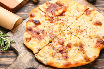 Board with tasty khachapuri on wooden background, closeup