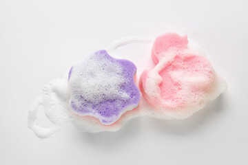 Star and duck shaped bath sponges with foam on white background