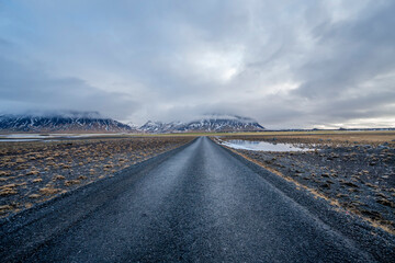 an empty asphalt road leads to mountains in Iceland