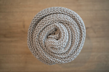 Gray knitted blanket rolled on bochen background. Home concept.