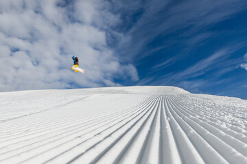 Close-up straight line rows of freshly prepared groomed ski slope piste with bright shining sun and...