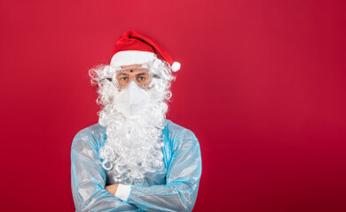Fototapeta na wymiar Doctor/nurse, in front of a red background, disguised as Santa Claus, wearing protective equipment for covid 19.