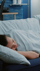Sick woman laying on couch with blanket feeling cold and having virus symptoms. Adult with seasonal...