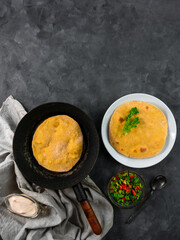 Homemade corn flatbread on frying pan cilantro green tomato salsa linen cloth. Handmade mexican tortilla vegetable. Traditional Indian Makki ki roti bread top view. Wheat flour dough authentic cuisine