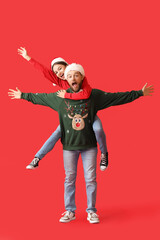 Happy young couple in stylish Christmas clothes on color background