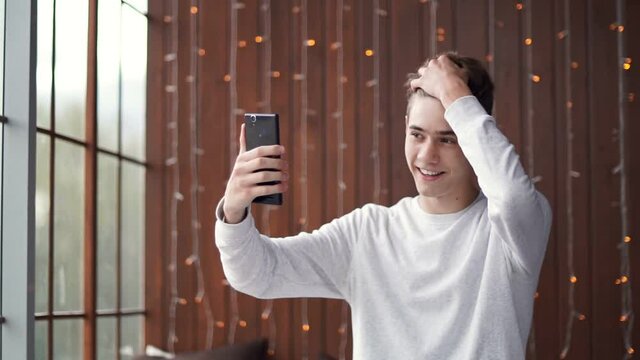 Narcissistic teenager takes pictures of himself on a smartphone. Young handsome guy.