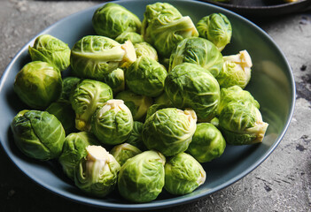 Bowl with raw Brussels cabbage on grey background, closeup