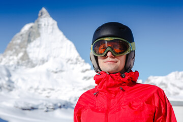 Happy man snowboarder posing with mountain landscape