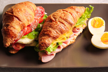 Plate with delicious croissant sandwiches on table, closeup