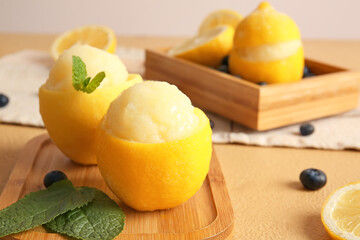 Board with tasty ice creams in lemon peels on color background