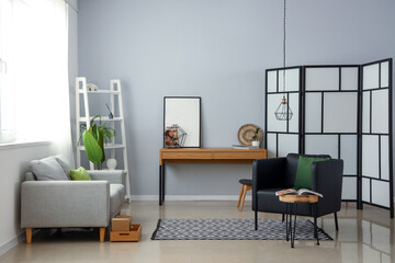 Naklejka na ściany i meble Interior of stylish living room with modern armchair and folding screen