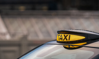 Taxi in Scotland, United Kingdom. Car sign with taxi word for public transportation with blurry...