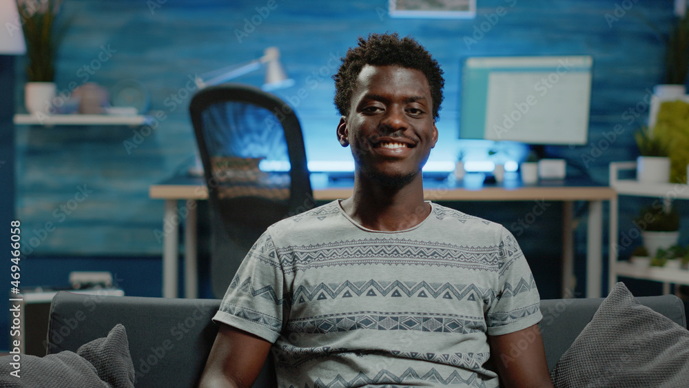 Poster close up of adult looking at camera and smiling on couch. portrait of man smiling after doing remote