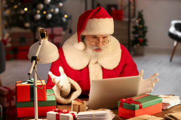 Surprised Santa Claus using laptop at home on Christmas eve