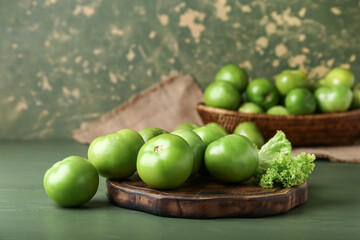 Wooden board with fresh green tomatoes on table