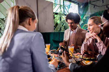 Group of people sitting in a restaurant at a business lunch.	