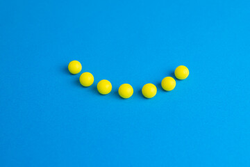 Vitamin C in yellow round tablets in the shape of a smile on a blue background