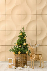 Wooden reindeer with Christmas tree and present near beige wall