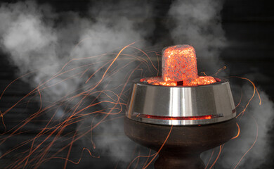 hot burning red coals for a hookah with sparks and smoke on a dark background.Traditional Asian relaxation. Space for text