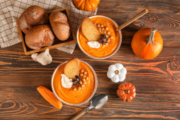 Composition with delicious pumpkin cream soup and buns on wooden background