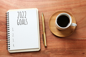 Obraz na płótnie Canvas Business concept of top view 2022 goals list with notebook, cup of coffee over wooden desk