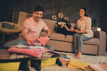 Photo of daddy put clothes luggage mommy sit sofa with daughter baby car seat ready for abroad...