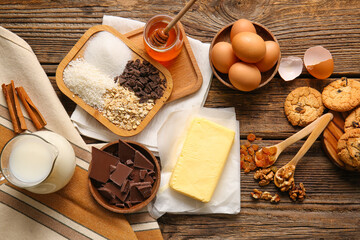 Fresh butter and ingredients for preparing homemade cookies on wooden background