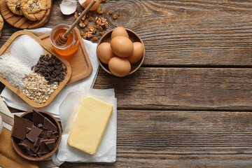 Fresh butter and ingredients for preparing homemade cookies on wooden background